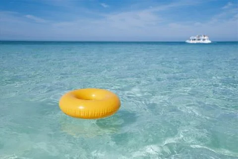 Floating ring on blue clear sea with white boat, shallow dof Stock Photos