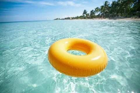 Floating ring on blue clear sea with beach, shallow dof Stock Photos