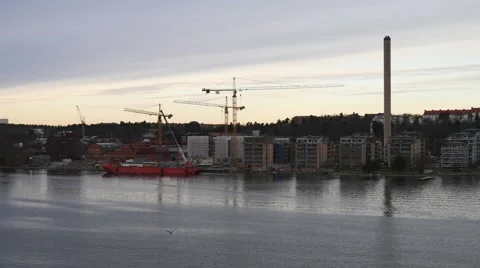 Floating on the river by buildings, tower cranes and red ship Stock Footage 65530037