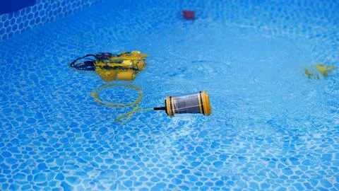 Floating robotic pool cleaner drifting across bright blue swimming pool water 스톡 사진