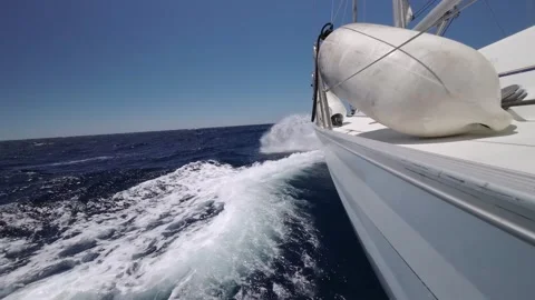 Floating sailing yacht with spread sails splitting the sea waves Stock Footage 240230745