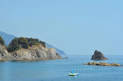 A floating slippery dip in a bay surrounded by rocks. Stock Photos