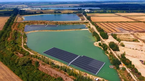 Floating solar power plant on quarry lakes. Photovoltaic array sits on green Vídeo Stock 346007487