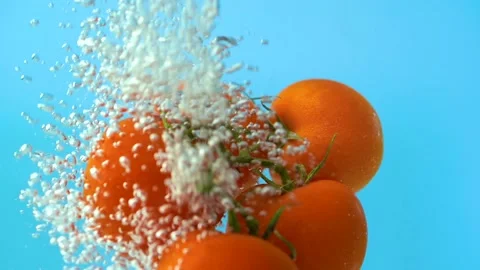 Floating tomatoes in water flow bubbles, blue background, close up slow motion Stock Footage 157456279