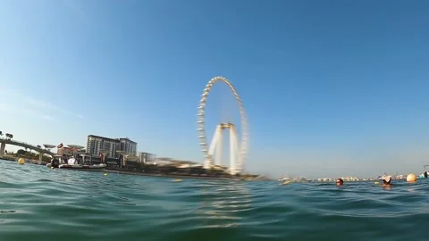 Floating up from under the water in front of the Ferris wheel in Dubai Stock Footage 221583328
