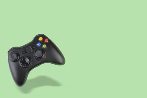 Floating videogame controller over green background with copy space Stock Photos