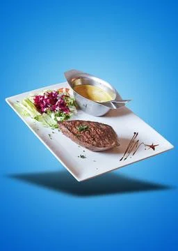 Floating Well done Beef steack with sauce and lettuce on blue gradient Stock Photos