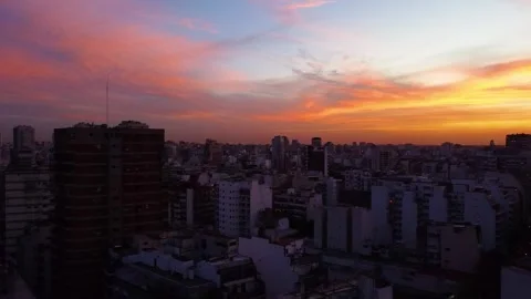 Flock of birds flying over buenos aires city during a colorful sunset Видео 339376487