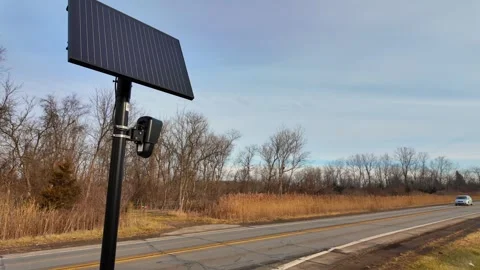 Flock camera security system with solar panel on roadside monitoring passing 库存影片 327647884