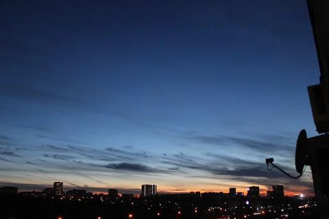 A flock of flying birds over a dark city, with a blue-orange sunset Foto stock