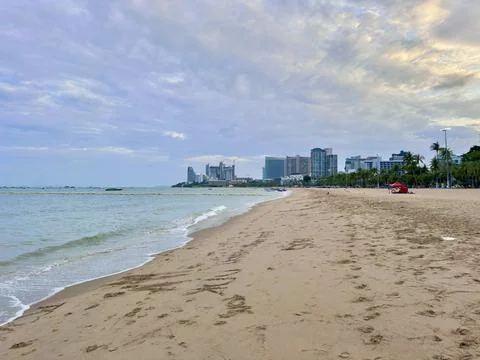 Flock of pigeons on an empty sandy beach next to modern buildings at Pattaya Stock Photos