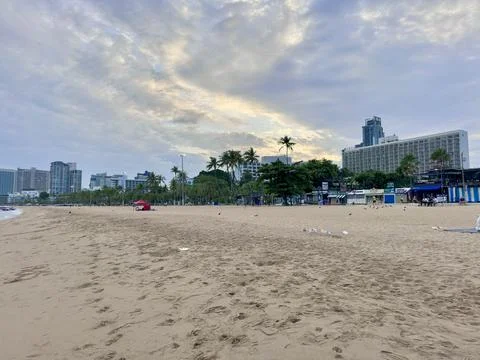 Flock of pigeons on an empty sandy beach next to modern buildings at Pattaya Stock Photos