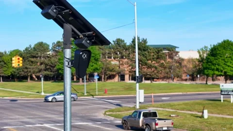 Flock traffic surveillance camera with solar panel monitoring a busy Stock Footage 337910244