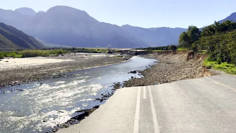 Flood damage with eroded river bank and large section or tar road washed away Vídeo Stock 345994698