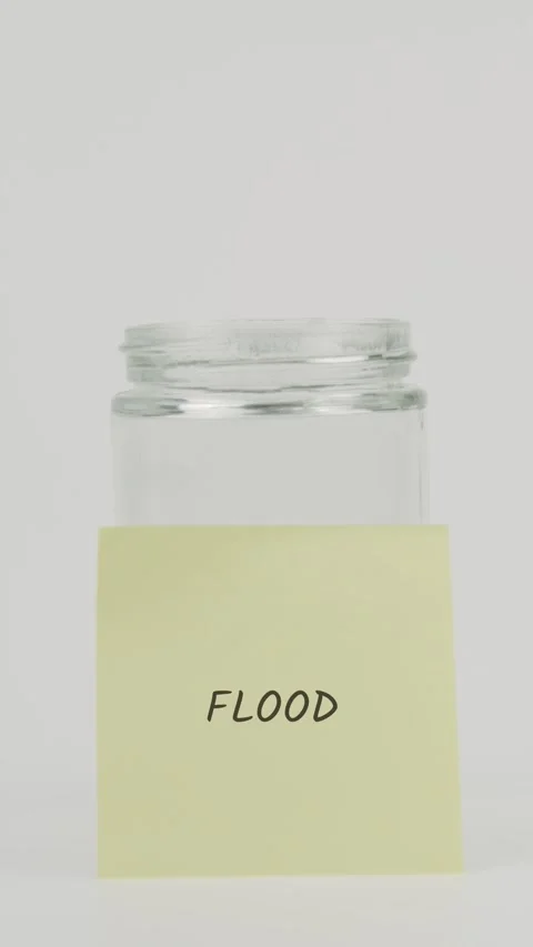 Flood text or word on yellow sticky note attached to glass jar with hand Stock Footage 311735134