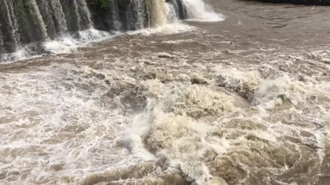 Flooded river flowing foaming through stone boulders rock Raging stream of .. Stock Footage 284430998
