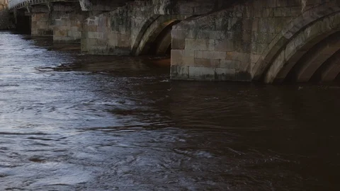 A flooded river flowing under a bridge Vídeo Stock 125574485