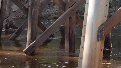 Flooded river flows swirls around pylons of old historic wooden bridge Stock-Footage 160382871