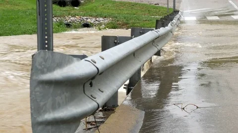 Flooded river starting to cross over road way Stock Footage 75076784
