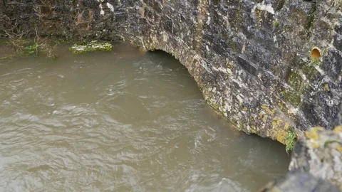 Flooded Stream flows under a bridge Stock Footage 126714135