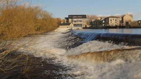 A flooded UK river creating a heavy waterfall downstream. Vídeo Stock 125582803