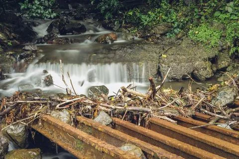 Flooding stream in long exposure while debris is trapped in cattle stops Stock Photos