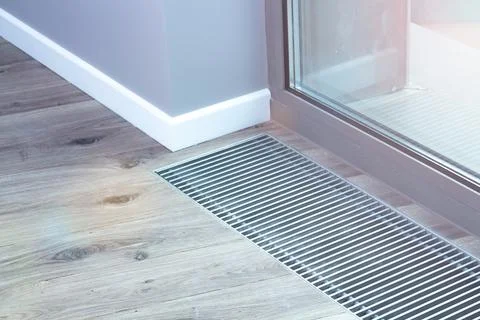 Floor convector heating metal grate built into the floor next to the window. Stock Photos