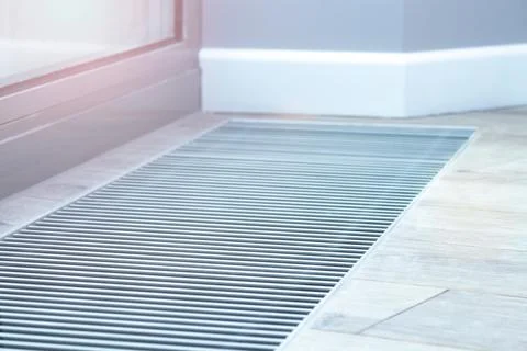 Floor convector heating metal grate built into the floor next to the window. Stock Photos