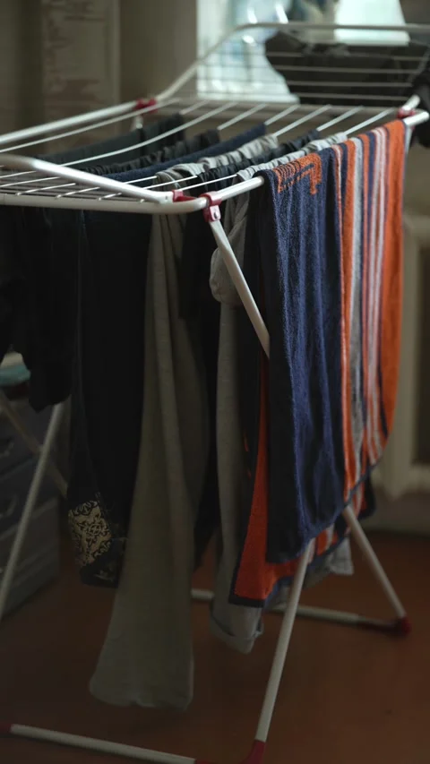 A floor laundry rack with wet clothes and colorful towels. Stock Footage 341241840