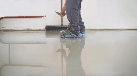 Floor leveling solution. A hired painter paints the floor in the apartment. T Stock Photos