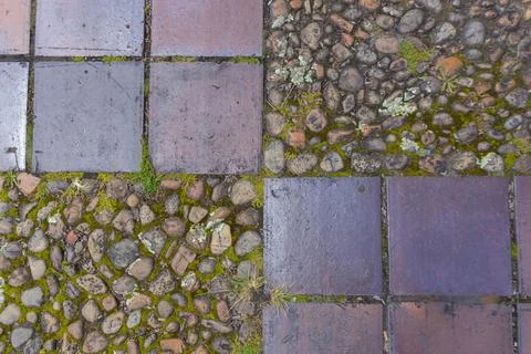 Floor pattern formed by square tiles and small, mossy river stones. Stock Photos