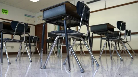 Floor view motion to the left showing empty school classroom with chairs under Stock Footage 138961715
