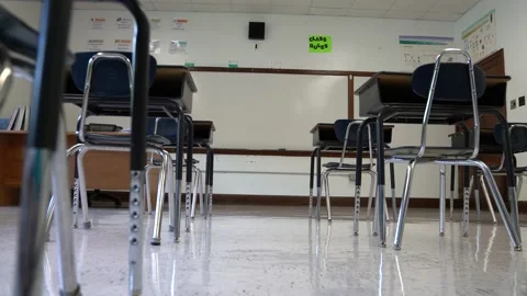 Floor view motion to the right showing empty school classroom with chairs under Stock Footage 138961688