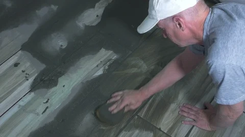 A flooring installer cleaning tile grout in a kitchen Stock Footage 106963281