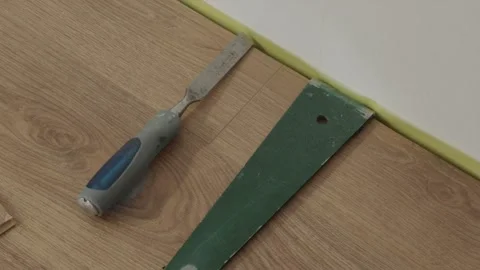 Flooring spacer and chisel tool near installed laminate edge Stock Footage 346159792