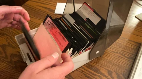 Floppy discs in storage case as a woman flips through disk of games and Stock Footage 124065552