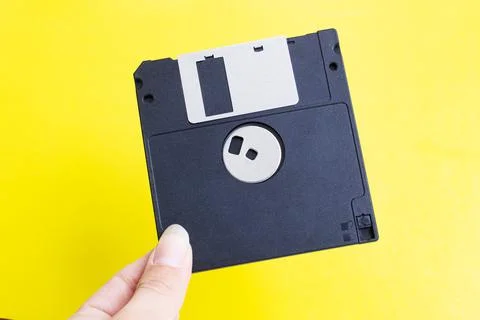 Floppy disk in hand on yellow background Stock Photos