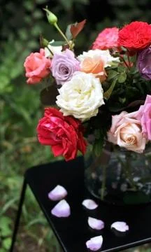 Floral bouquet of different multi colored roses in a glass vase on a dark tab Stock Photos