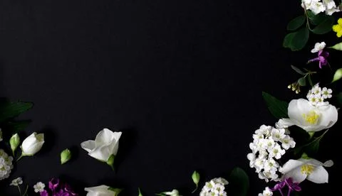 Floral frame made of different spring flowers on black background. Flowers flat Stock Photos