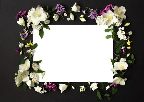 Floral frame made of different spring flowers on black background. Flowers flat Stock Photos