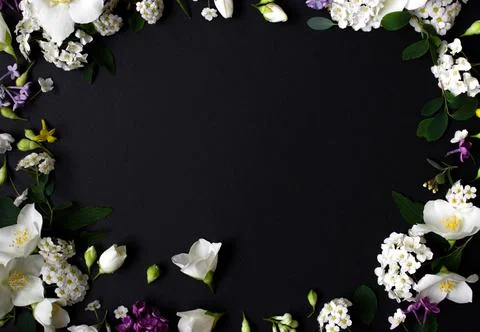 Floral frame made of different spring flowers on black background. Flowers flat Stock Photos