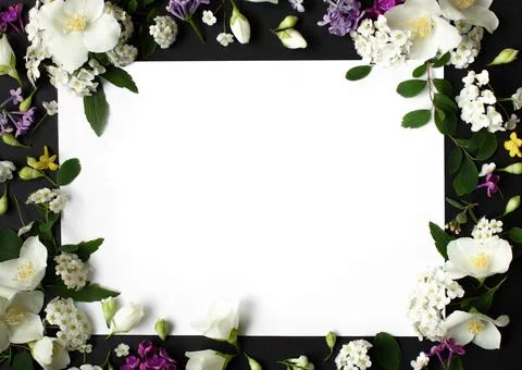 Floral frame made of different spring flowers on black background. Flowers flat Stock Photos