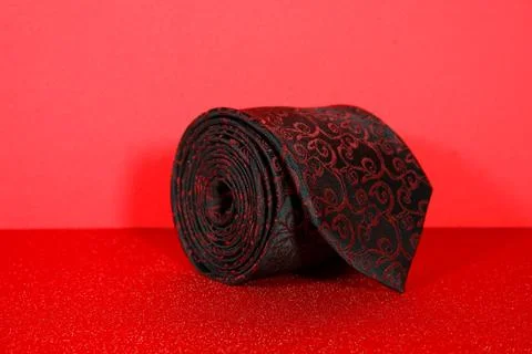 A floral pattern classic tie rolled isolated on red background closeup view Stock Photos