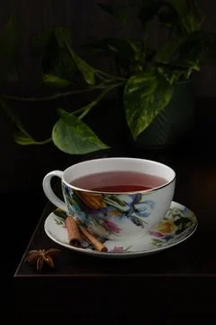 Floral-patterned teacup filled with red tea sits on a matching saucer Stock Photos