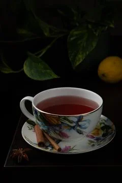 Floral-patterned teacup filled with red tea sits on a matching saucer. Stock Photos