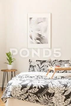 Floral sheets on the bed with a wooden tray in a bright bedroom interior Stock Photos