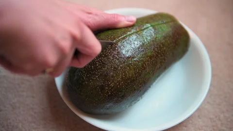 Florida avocado green fruit hands cutting by kitchen knife in half on plate Vídeo Stock 336780377