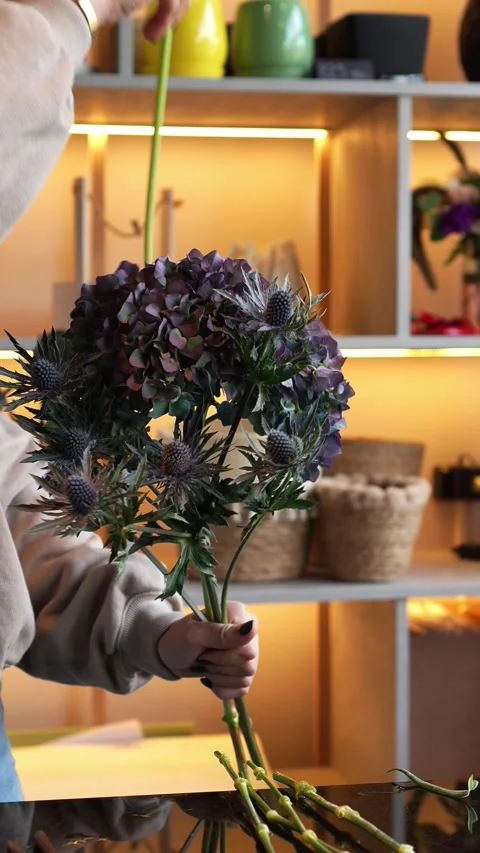 Florist creates a bouquet. Adds hydrangea, eryngium, calla lilies. Cozy autumn f Stock Footage 318554271