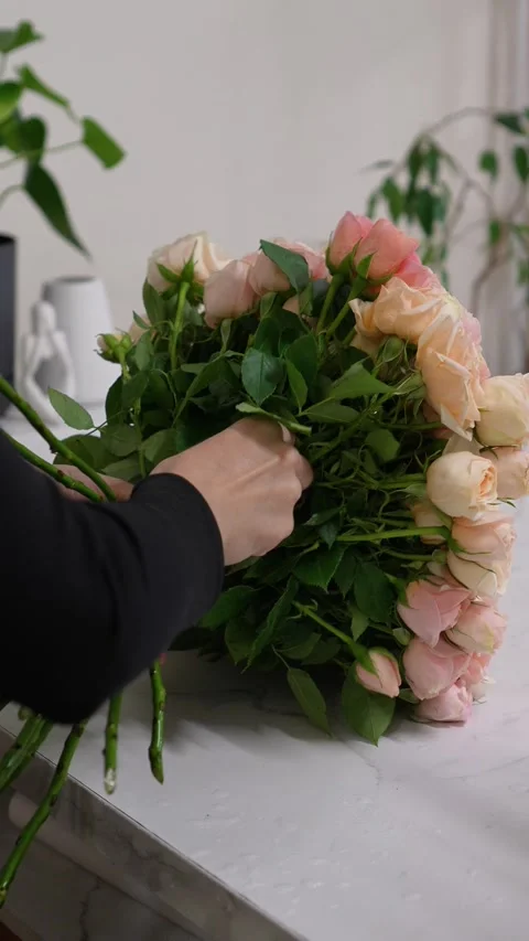 Florist forms a bouquet on the table from pink bush rose Christie Stock Footage 317961798