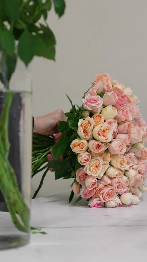 Florist forms a bouquet on the table from pink bush rose Christie Stock Footage 317961809